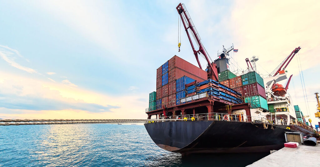 a crane loading cargo containers onto a large ship