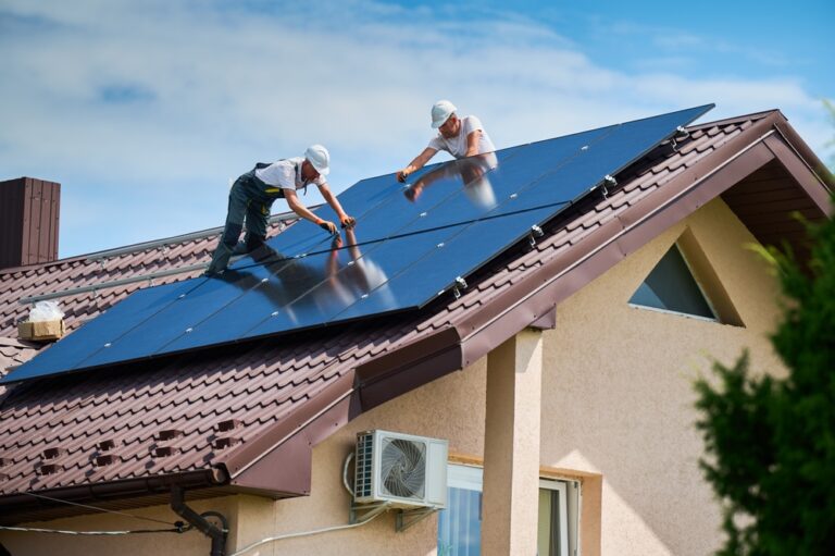 two men on the roof of a house installing solar panels